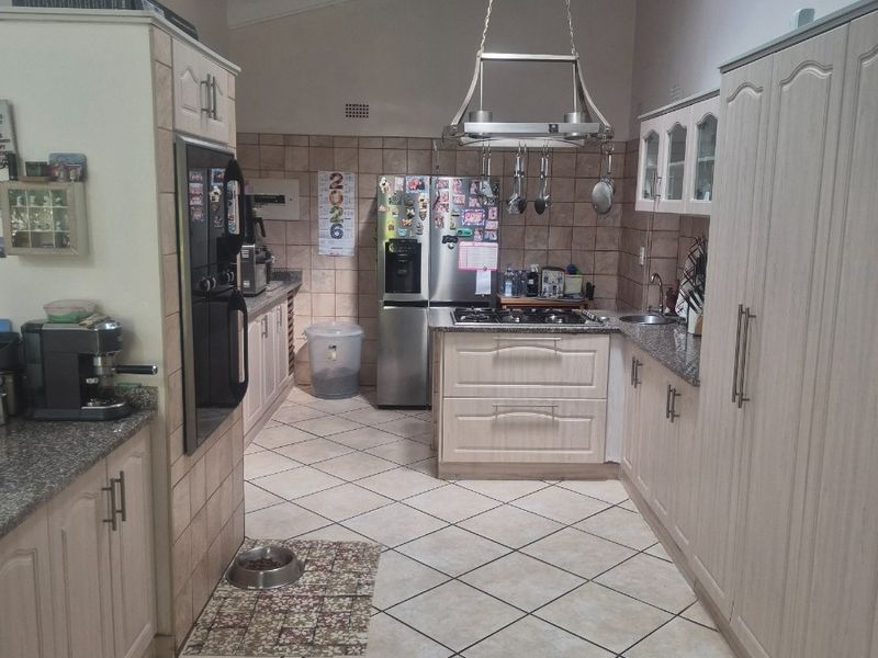 A functional kitchen featuring light-toned cabinetry, granite countertops, a gas hob, and a vaulted ceiling, offering a practical layout for daily cooking.