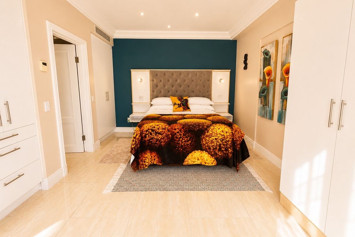 A well-maintained bedroom featuring tiled flooring, built-in cupboards, recessed ceiling lighting, and a stylish integrated headboard against a feature wall.