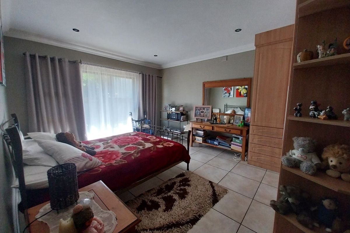 A spacious bedroom featuring tiled flooring, built-in cabinetry, and a sliding glass door providing natural light.
