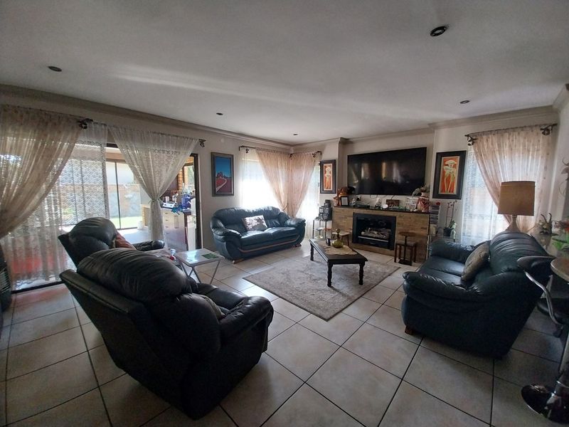 Spacious living room featuring tiled flooring, a built-in fireplace with stone surround, and sliding glass doors providing access to the outdoor area.