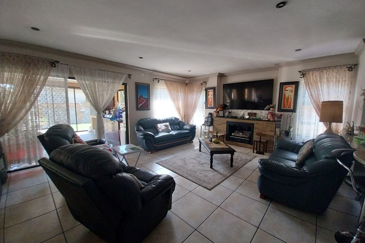Spacious living room featuring tiled flooring, a built-in fireplace with stone surround, and sliding glass doors providing access to the outdoor area.