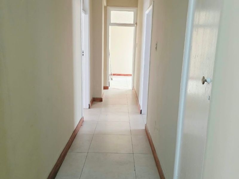 A functional, empty hallway featuring neutral tiled flooring and multiple internal doorways, providing access to various rooms within the home.
