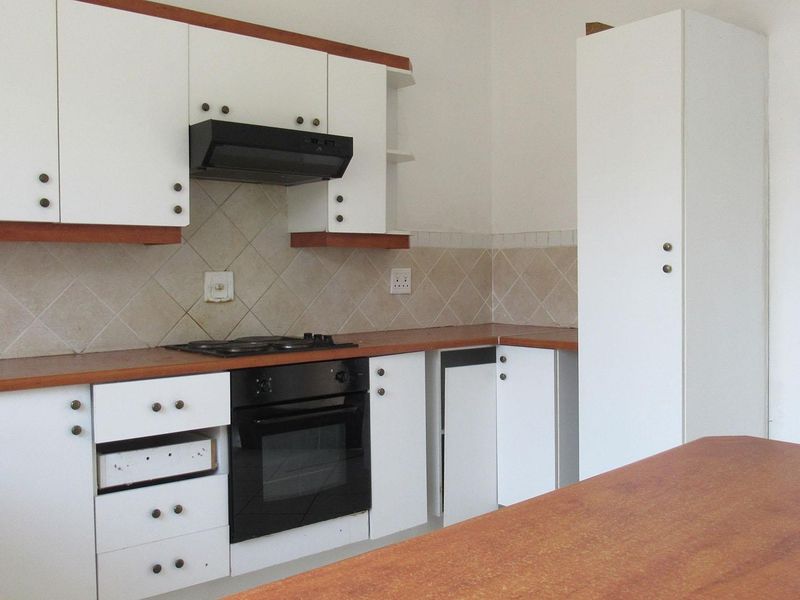 A functional kitchen featuring white cabinetry, laminate countertops, a built-in oven, and a gas hob with a tiled backsplash.