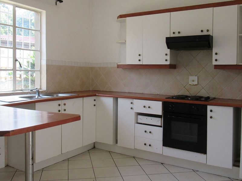 A functional kitchen featuring white cabinetry, laminate countertops, built-in oven, gas hob, and tiled backsplash, offering a clean canvas for potential updates.