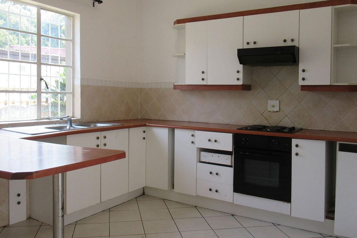 A functional kitchen featuring white cabinetry, laminate countertops, built-in oven, gas hob, and tiled backsplash, offering a clean canvas for potential updates.