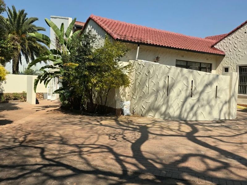 Front exterior view of a cottage featuring a terracotta tiled roof, textured facade, and a paved driveway area.