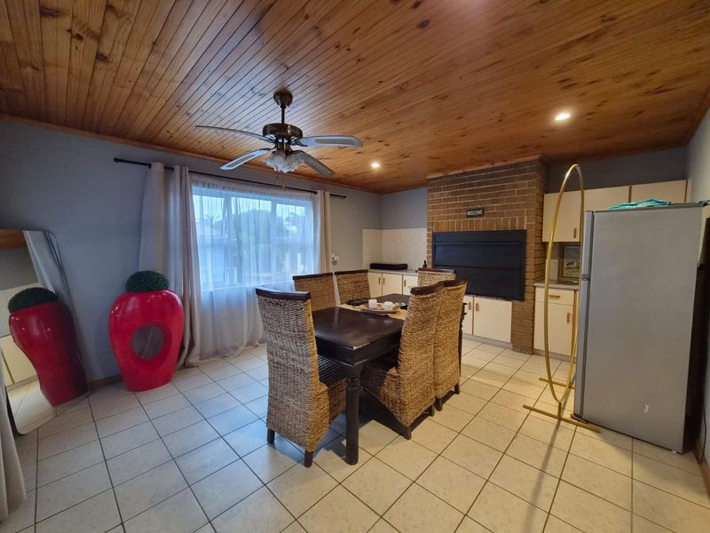 Open plan dining area featuring a timber ceiling, tiled floors, and a built-in brick fireplace.