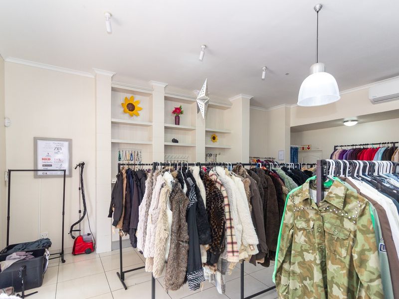 Retail space interior featuring tiled flooring, built-in display shelving, and integrated ceiling and pendant lighting with a wall-mounted air conditioning unit.