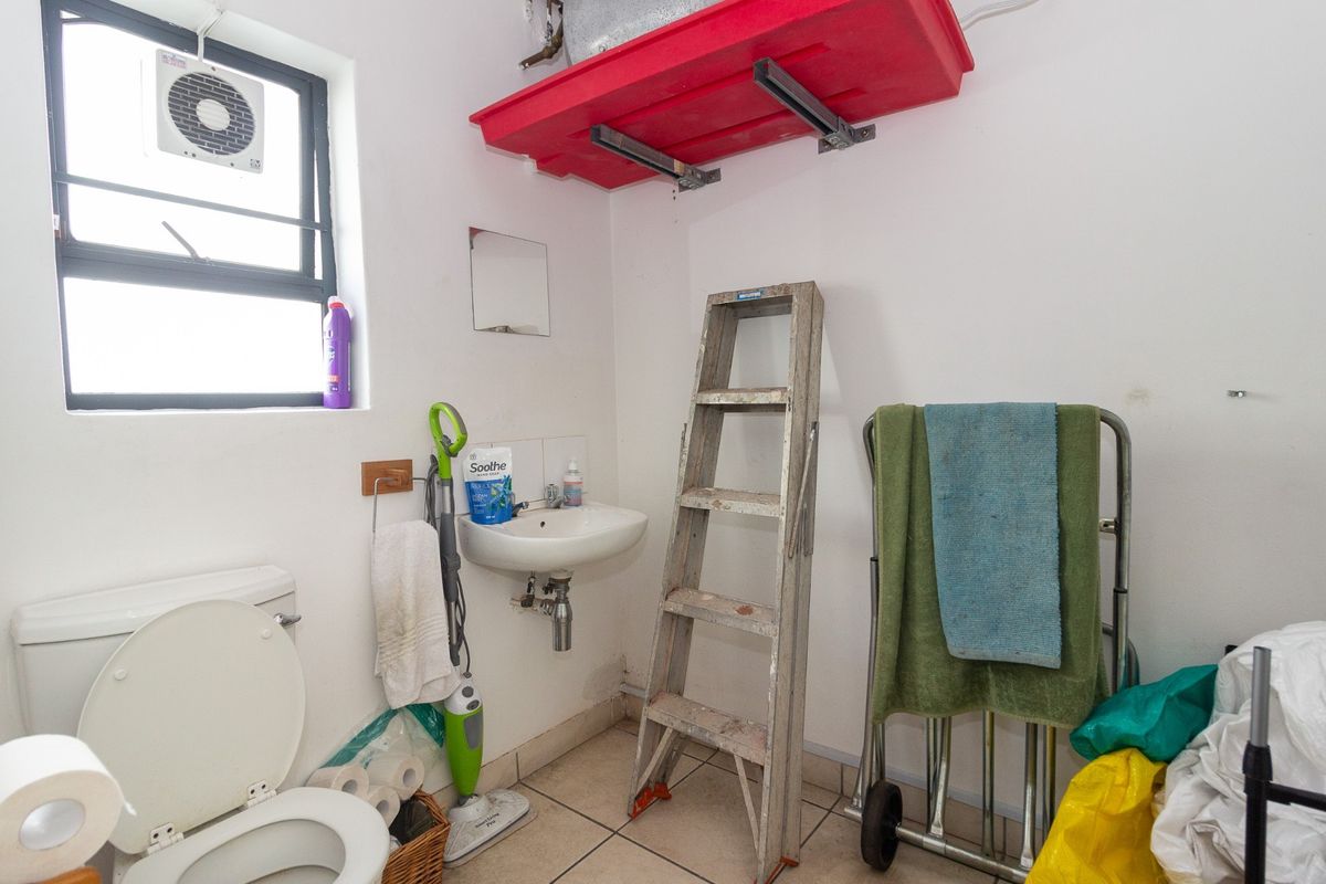 A functional bathroom space featuring a wall-mounted basin, toilet, and extractor fan, requiring cosmetic updates to improve the overall finish and condition.