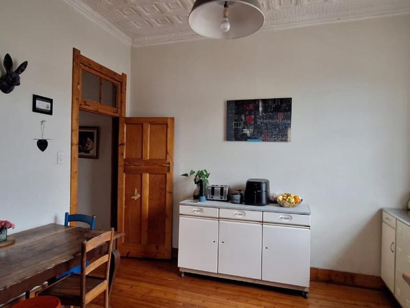 A kitchen area featuring original hardwood flooring, a decorative pressed metal ceiling, and classic timber door frames, offering a character-filled space for renovation.