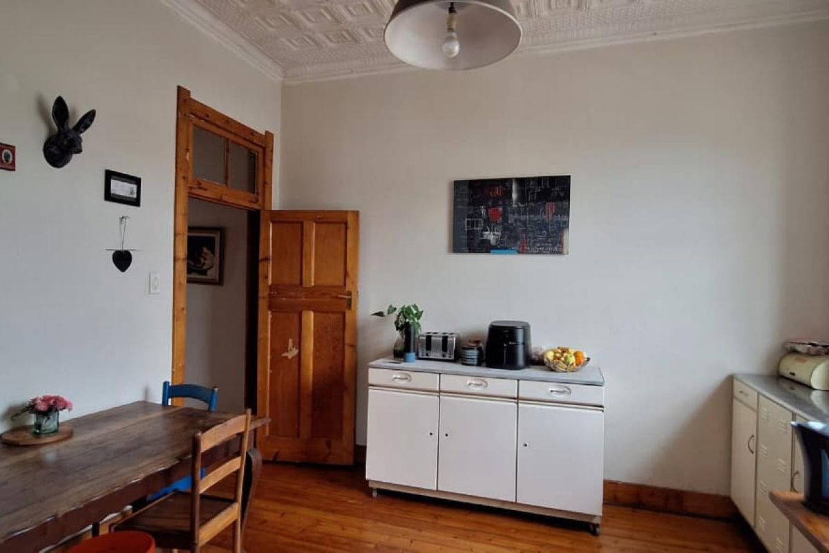 A kitchen area featuring original hardwood flooring, a decorative pressed metal ceiling, and classic timber door frames, offering a character-filled space for renovation.