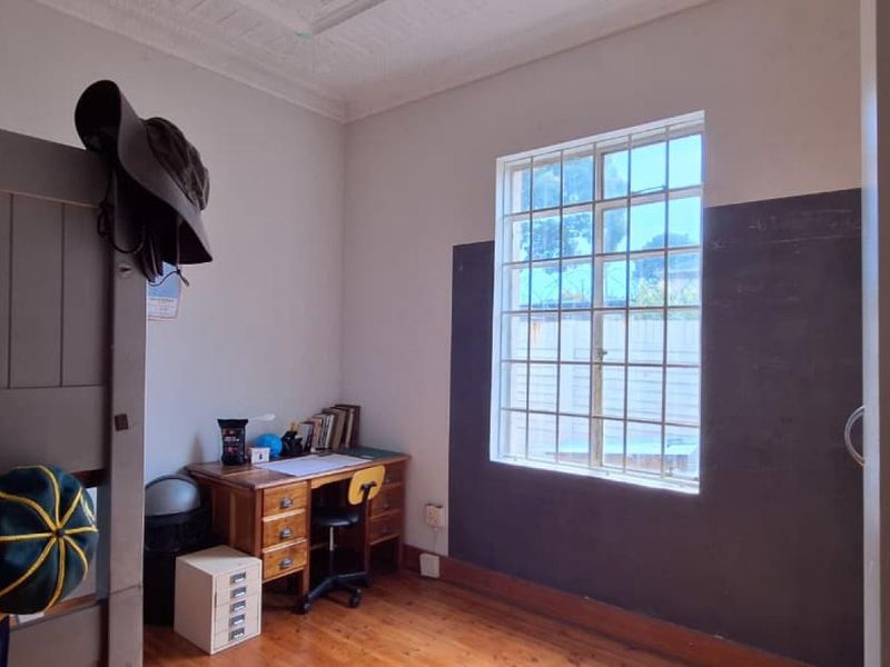 A bedroom featuring original timber flooring, security bars on the window, and decorative ceiling cornicing.