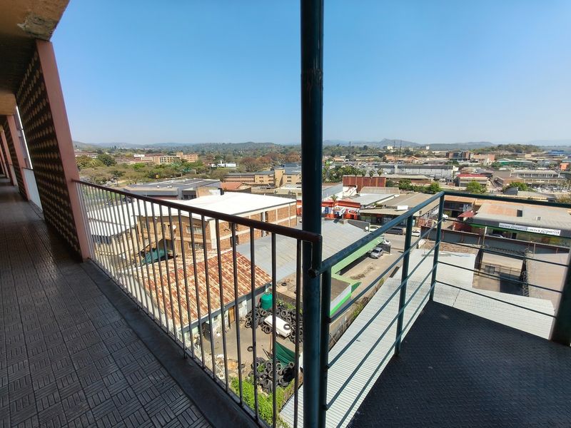 An elevated balcony featuring a metal balustrade and tiled flooring, offering an expansive view of the surrounding urban landscape.
