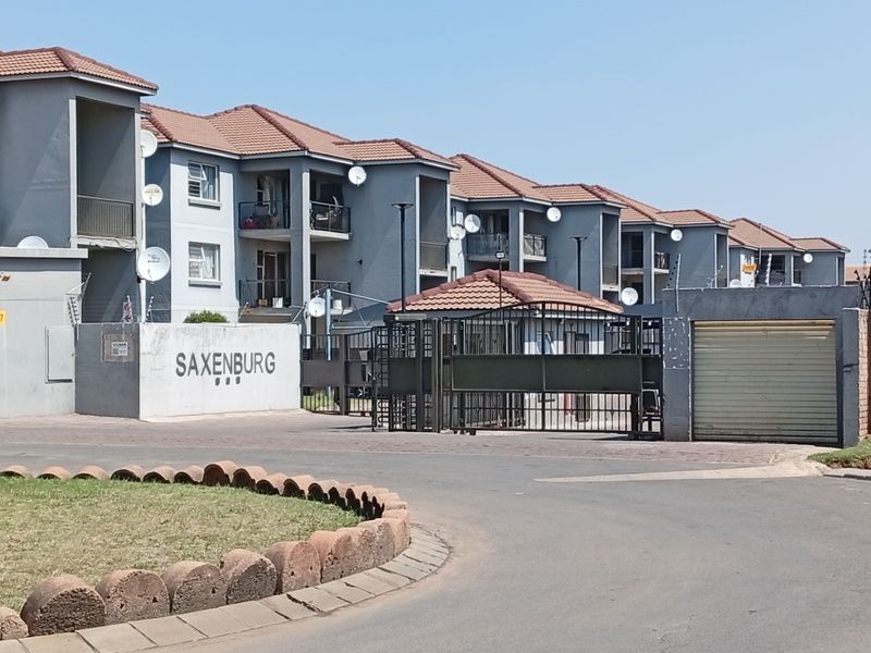 Front view of the Saxenburg residential complex featuring multi-story apartment blocks, secure gated entrance, and paved driveway access.