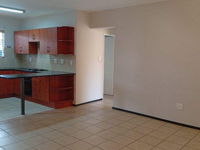 Open plan kitchen and living area featuring tiled flooring, built-in wooden cabinetry, and integrated cooking appliances.