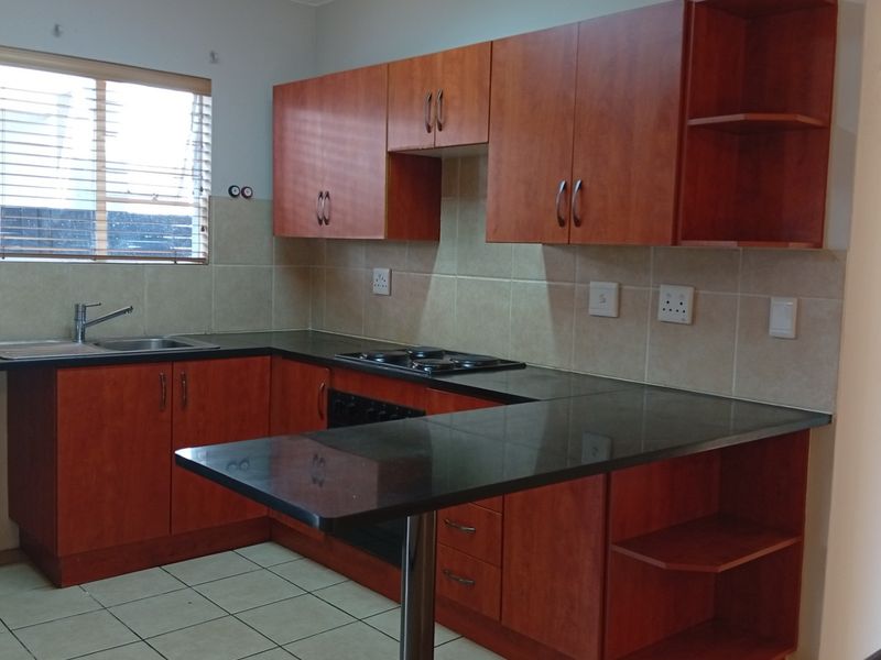 A functional kitchen featuring wood-finish cabinetry, granite countertops, a built-in hob and oven, and a breakfast nook, offering a clean and practical workspace.