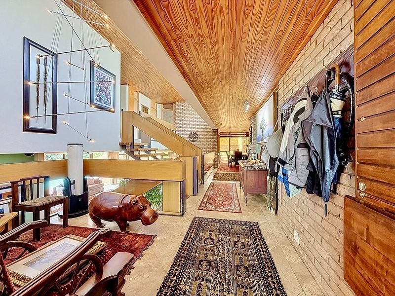 Spacious entrance hall featuring a warm timber-clad ceiling, exposed brick walls, and elegant stone flooring, leading into the open-plan living areas.