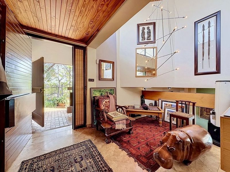 Welcoming entrance hall featuring a high timber-clad ceiling, stone tile flooring, and a seamless transition to the outdoor patio area.