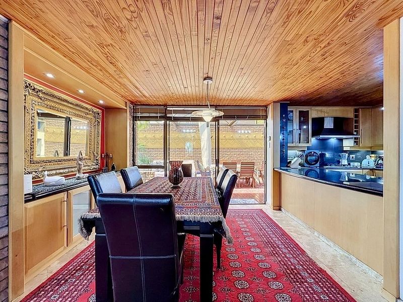 Open plan dining and kitchen area featuring a warm timber ceiling, granite countertops, and direct access to the outdoor patio through sliding glass doors.