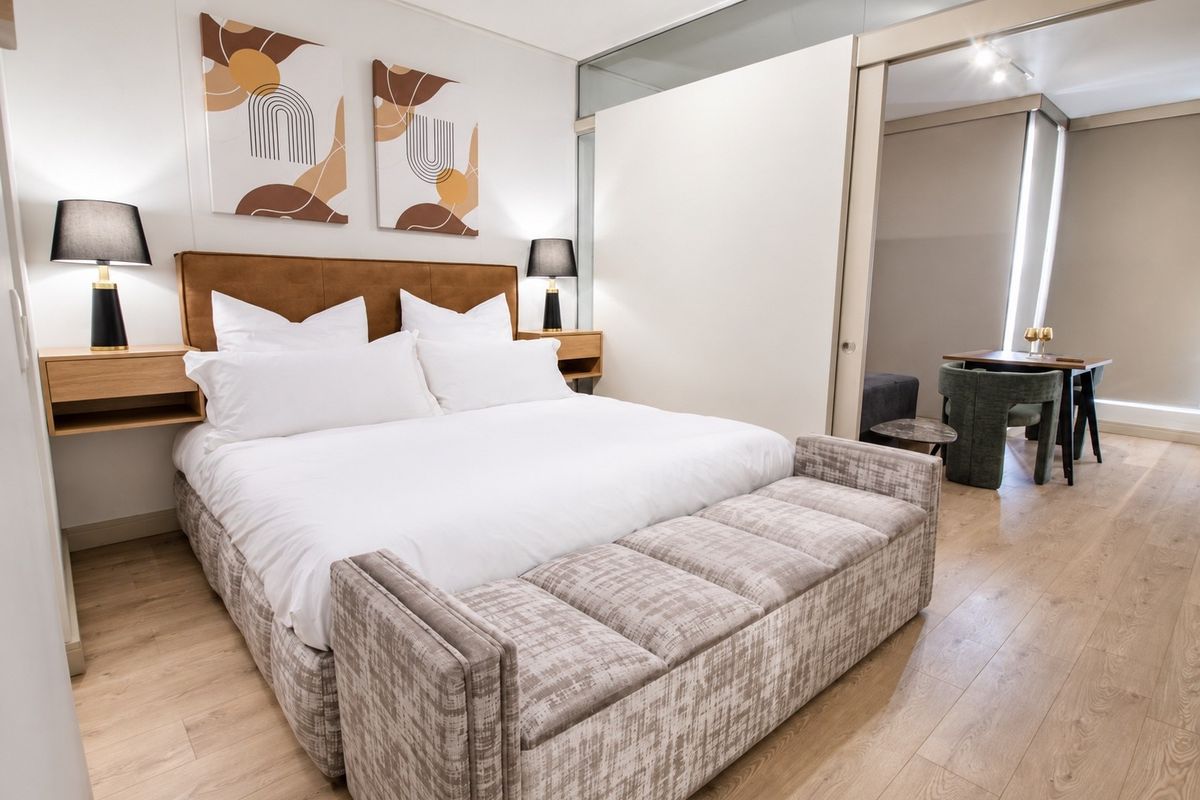 A modern, well-maintained bedroom featuring laminate flooring and a sleek sliding glass partition that opens into an adjacent living or dining space.