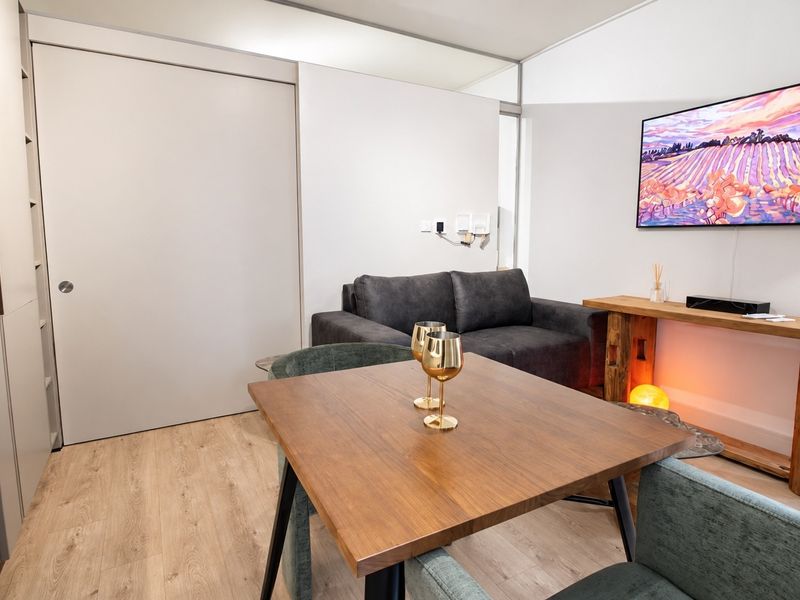 A modern open-plan living area featuring light laminate flooring, neutral walls, and integrated cabinetry, creating a clean and functional space.