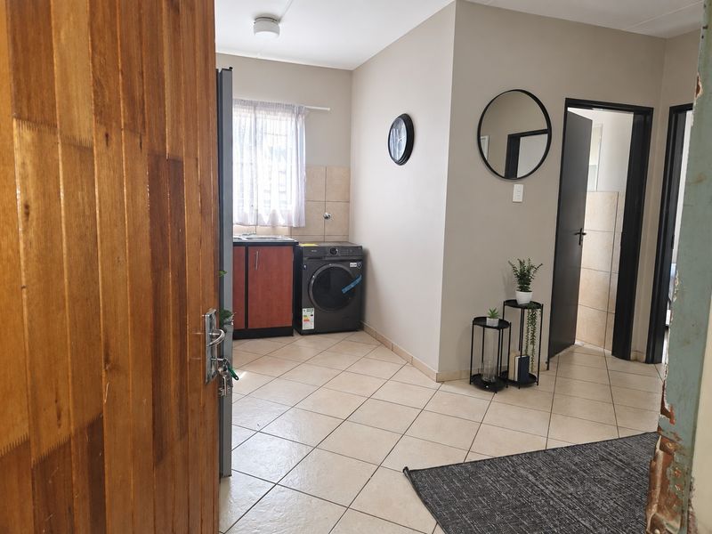 A functional laundry area featuring tiled flooring, built-in cabinetry with a sink, and a tiled splashback, providing a practical utility space.