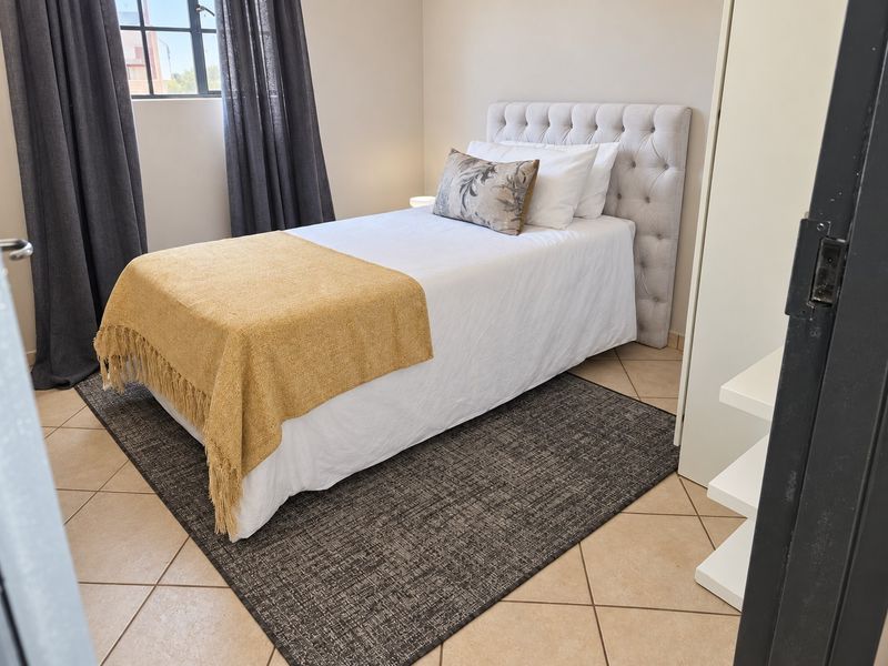 A well-maintained bedroom featuring tiled flooring and a built-in cupboard, offering a clean and functional living space.