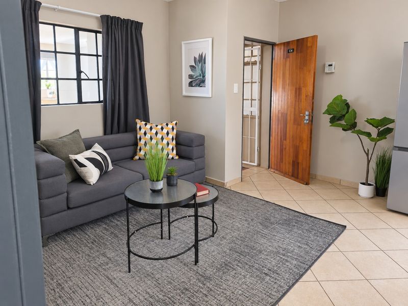 A well-maintained living area featuring neutral wall tones, tiled flooring, and a steel-framed window, providing a clean and functional space.