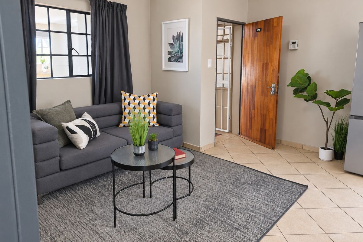A well-maintained living area featuring neutral wall tones, tiled flooring, and a steel-framed window, providing a clean and functional space.