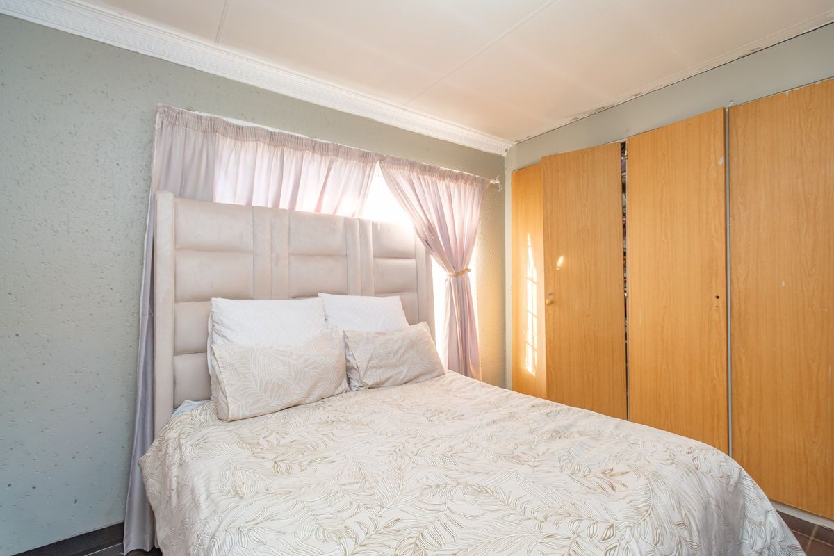 A bedroom featuring built-in wooden cupboards, textured wall finishes, and decorative ceiling cornicing, requiring minor maintenance to the ceiling finishes.