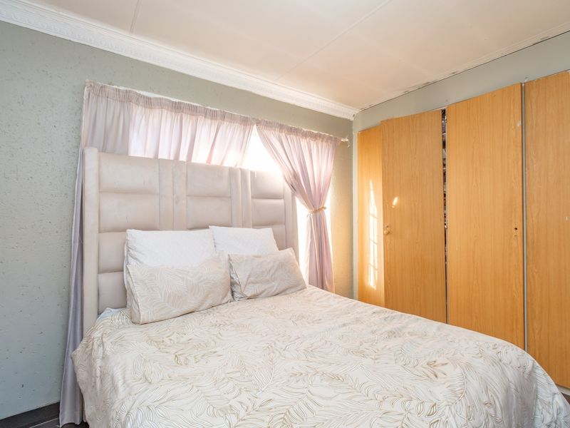A bedroom featuring built-in wooden cupboards, textured wall finishes, and decorative ceiling cornicing, requiring minor maintenance to the ceiling finishes.
