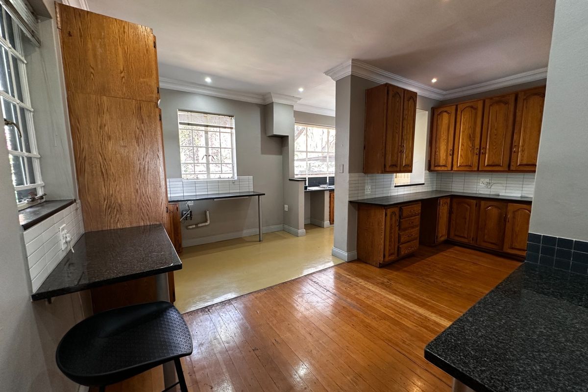 Spacious kitchen featuring traditional wooden cabinetry, granite countertops, tiled backsplash, and hardwood flooring, offering a functional layout with ample storage space.