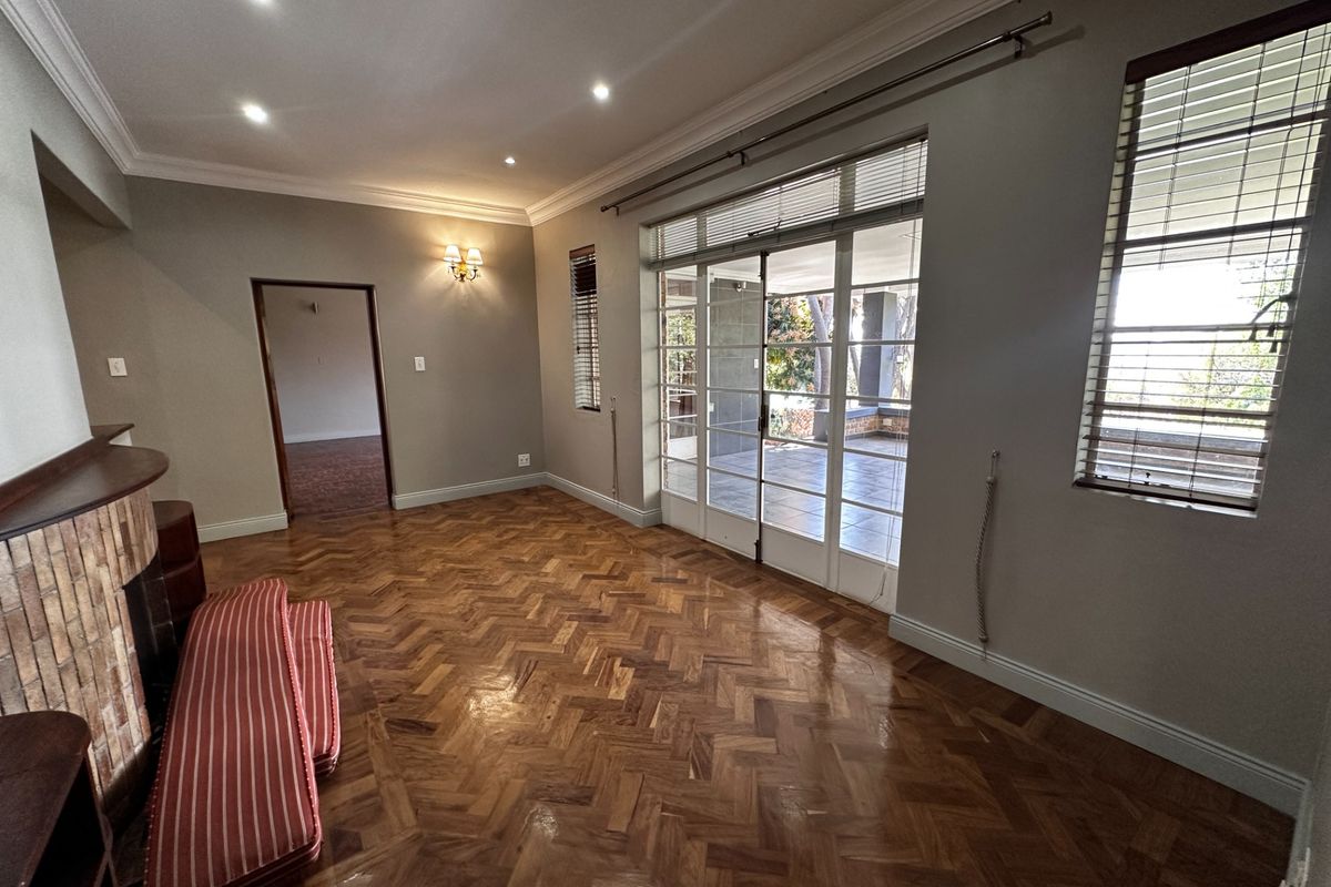 Spacious living room featuring polished herringbone parquet flooring, a brick fireplace, and large sliding glass doors providing access to the patio.