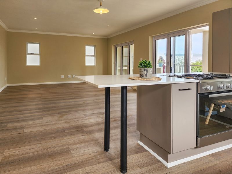 Spacious open-plan living area featuring modern laminate flooring, recessed lighting, and a functional kitchen island with a built-in gas stove and oven.