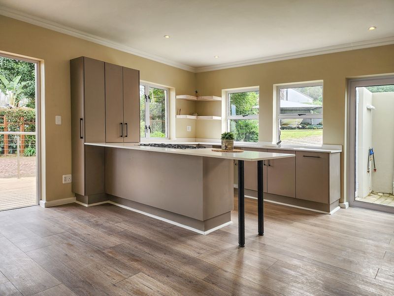 Modern kitchen featuring neutral cabinetry, stone countertops, integrated gas hob, and ample natural light with direct access to outdoor areas.