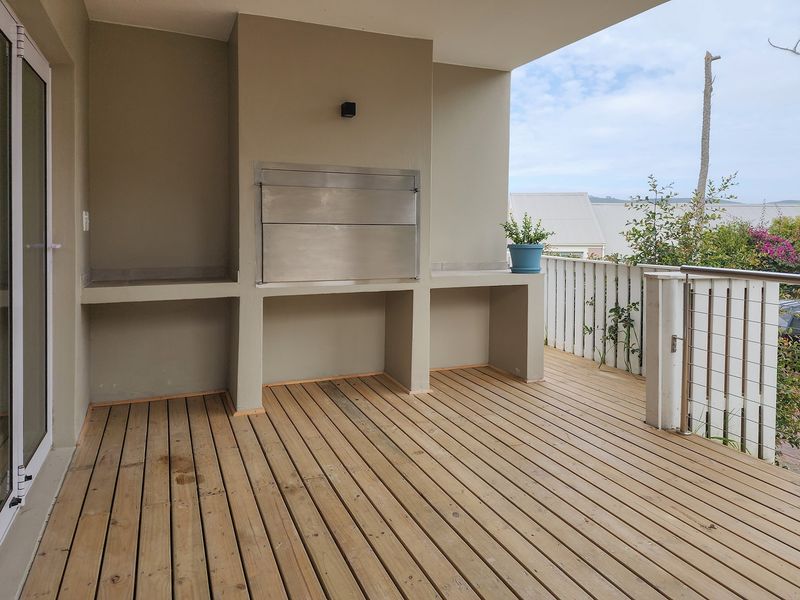 Covered patio featuring timber decking and a built-in stainless steel braai, offering an ideal space for outdoor entertaining.