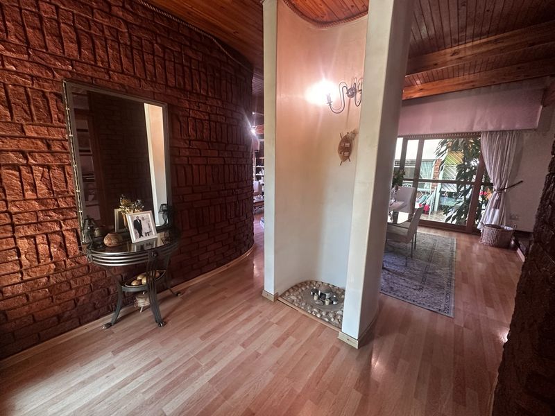 Entrance foyer featuring a curved exposed brick wall, timber ceiling, and a central feature pillar with a decorative pebble floor inlay.