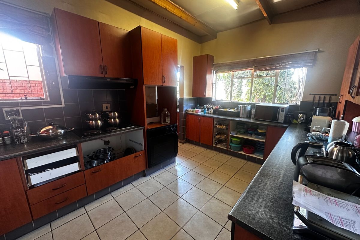 A functional kitchen featuring wooden cabinetry, tiled flooring, exposed timber ceiling beams, and a built-in oven with an extractor fan.