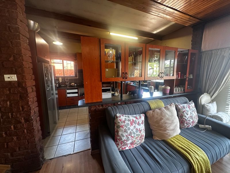 Open-plan living and kitchen area featuring exposed brickwork, timber ceilings, and built-in cabinetry with a breakfast bar partition.
