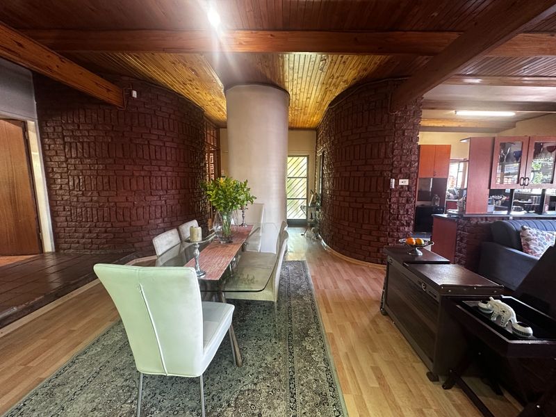 Open plan living and dining area featuring distinctive exposed brick walls, timber ceilings with exposed beams, and a central structural column.