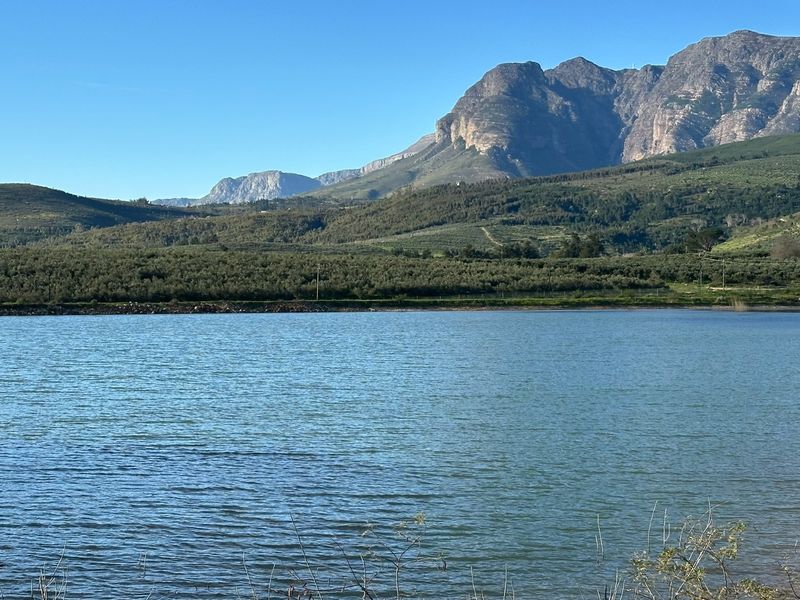 A scenic view of a tranquil lake set against a backdrop of rolling hills and majestic mountains.
