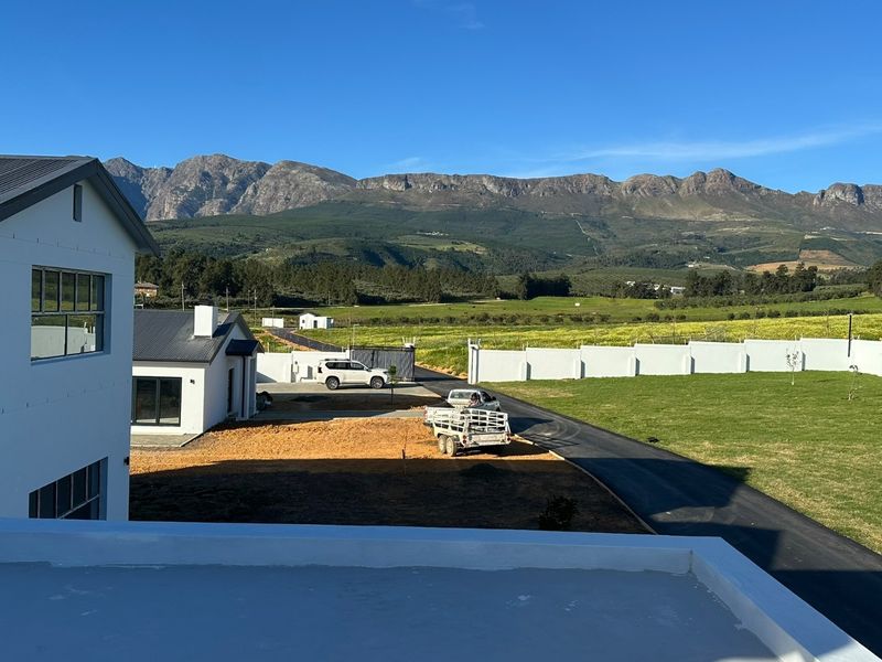 Elevated view overlooking the property grounds, driveway, and surrounding landscape with scenic mountain vistas in the background.