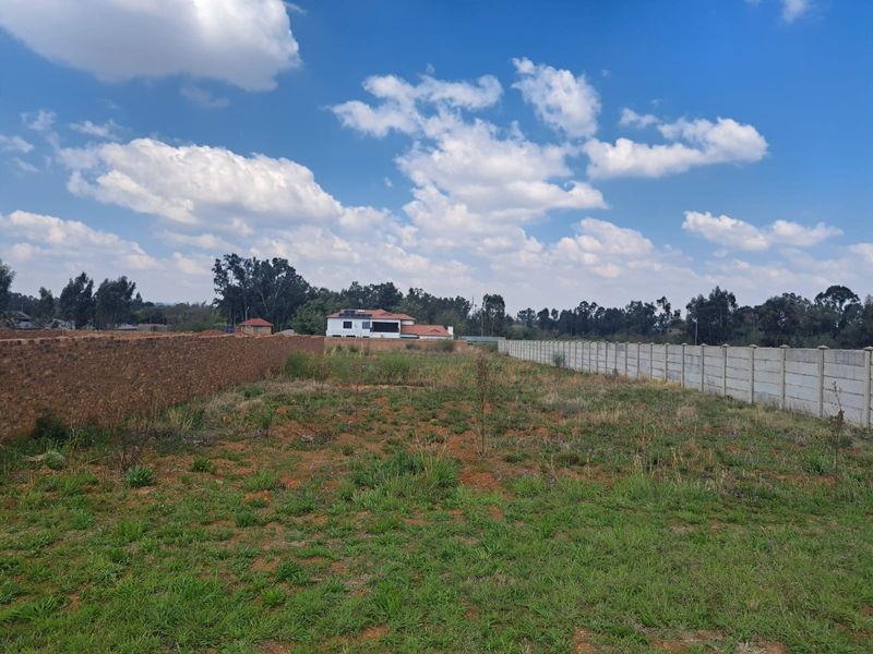 A vacant residential plot featuring established brick and precast concrete boundary walls, offering a clear space for future development.