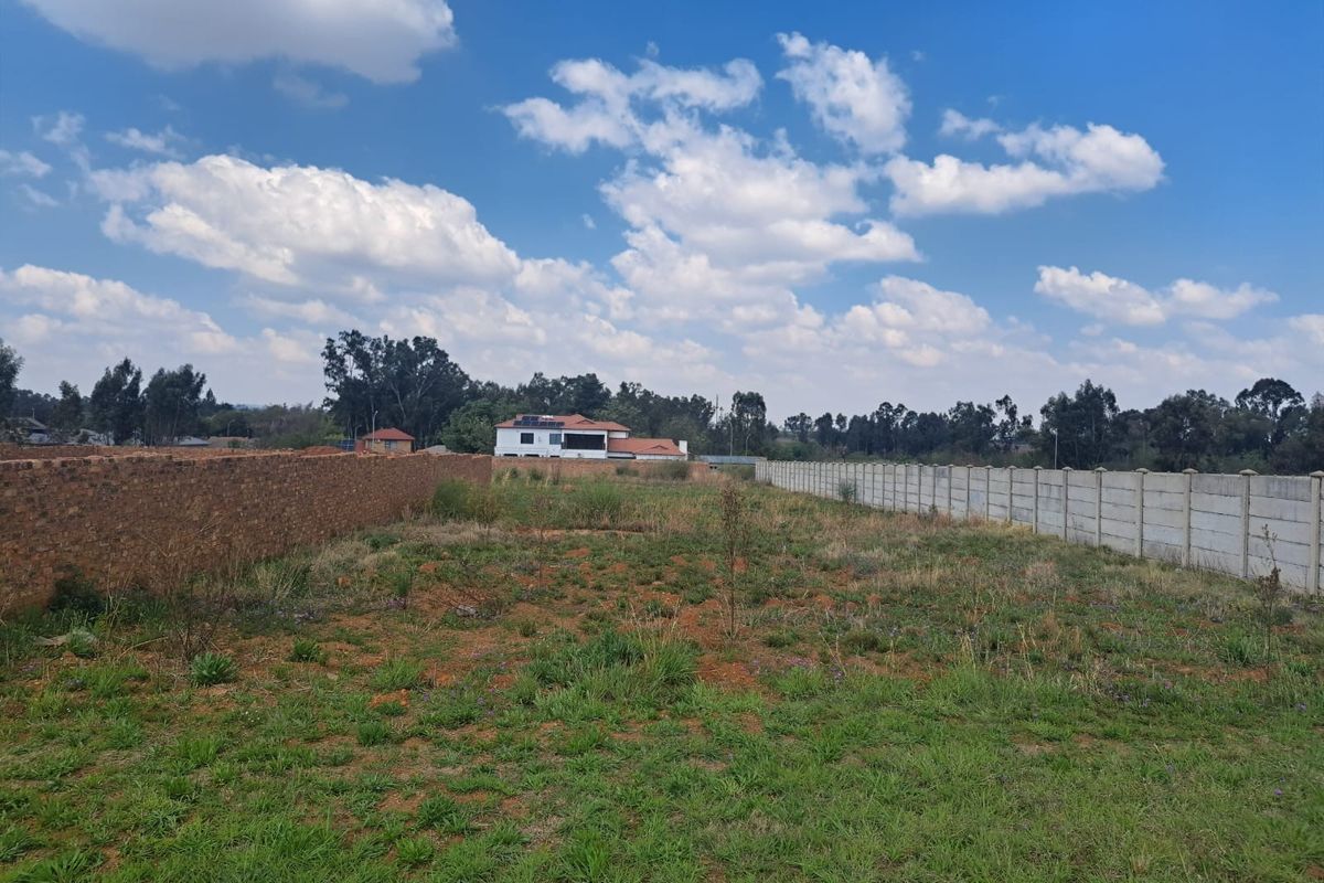 A vacant residential plot featuring established brick and precast concrete boundary walls, offering a clear space for future development.