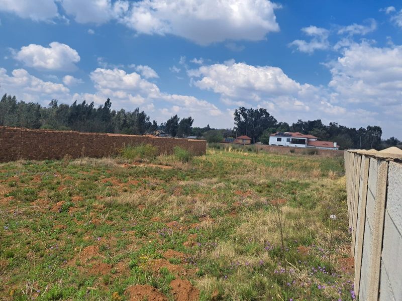 A vacant residential plot featuring established brick and precast concrete boundary walls, offering a clear space for future development.