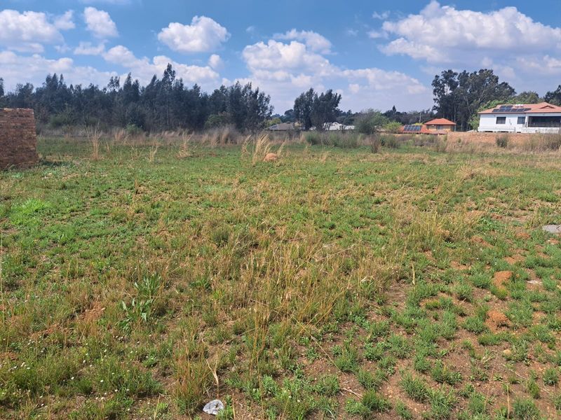 A view of an undeveloped residential plot of land featuring natural grass cover and surrounding neighborhood structures.
