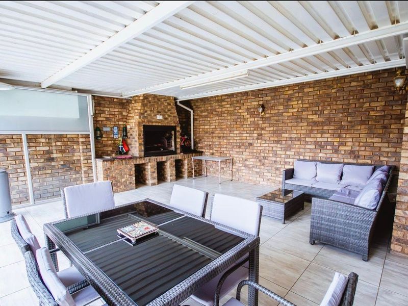 Covered outdoor patio featuring a built-in brick braai, tiled flooring, and exposed brick walls, ideal for alfresco dining and entertaining.