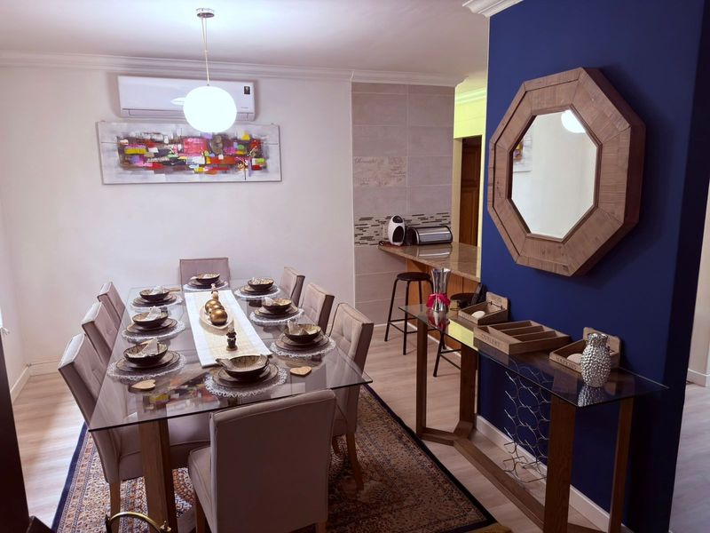 A well-presented dining area featuring laminate flooring, a split-system air conditioner, and a breakfast bar with granite countertops and tiled splashback.