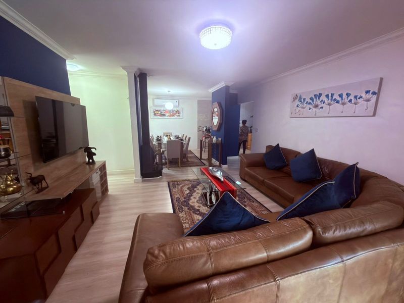 Spacious open-plan living and dining area featuring laminate flooring, modern lighting, and a built-in media unit, creating a comfortable and functional living space.