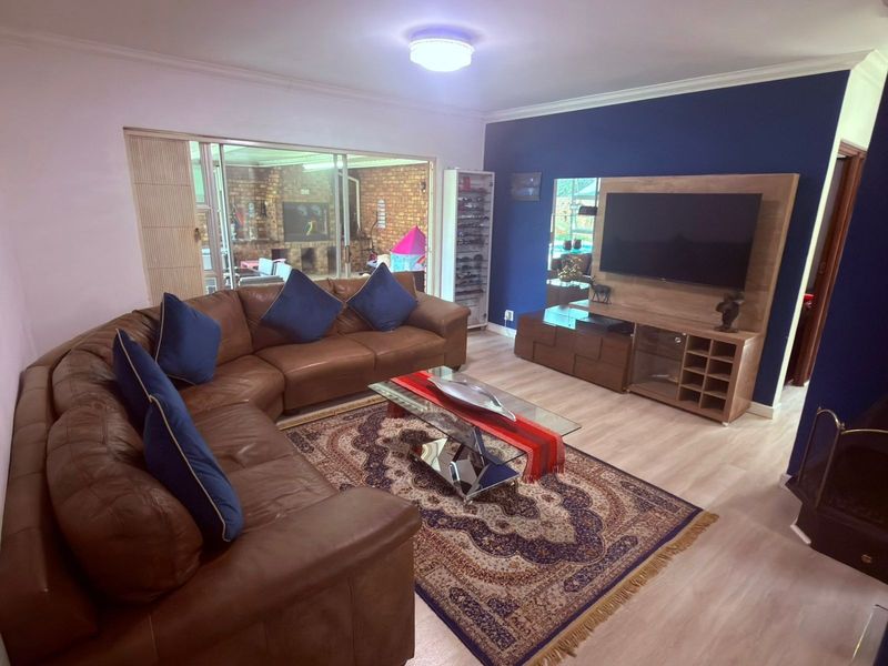 A comfortable living room featuring laminate flooring, cove cornicing, and a large sliding glass door providing access to the outdoor patio area.